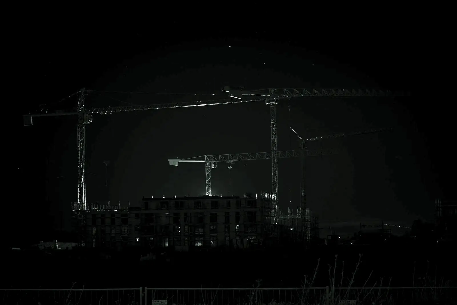 Construction cranes over a building site at night