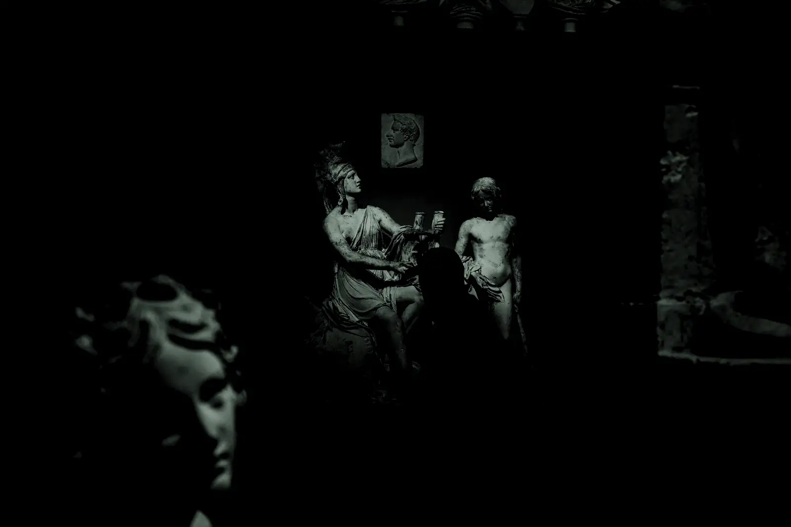 Ancient sculptures lit by a spotlight in a dark museum